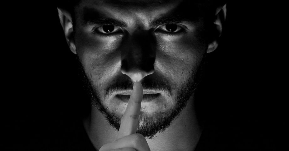 man with finger to lips to silence