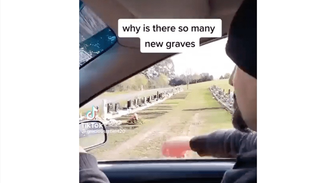 man in car observing fresh graves in cemetery