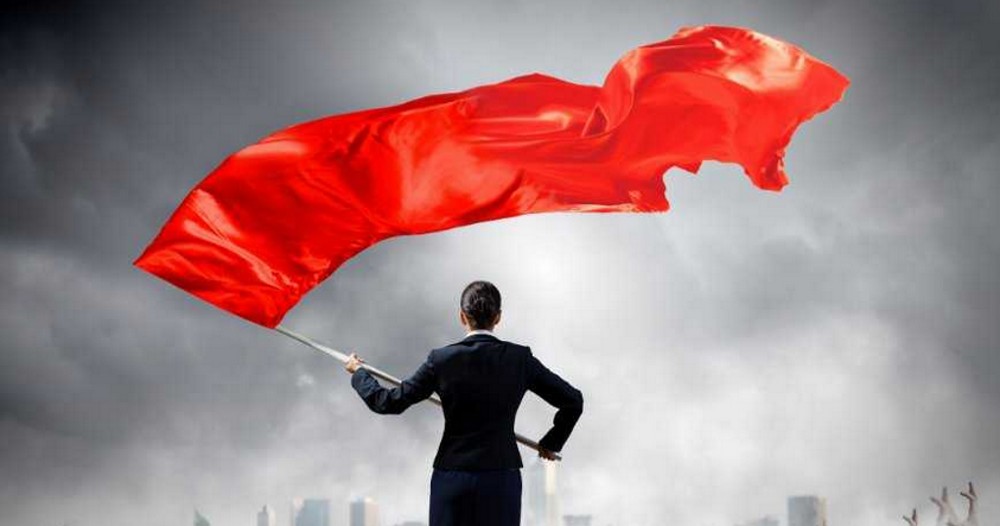 rear view of black suited woman waving large red flag