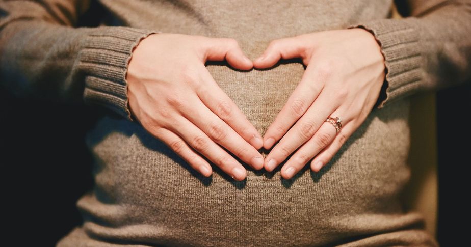 two hands holding pregnant stomach