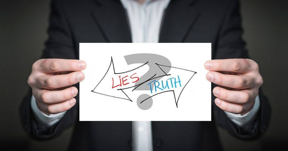 two hands holding 'truth lies' signs