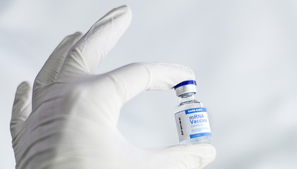 gloved hand holding mrna vaccine vial